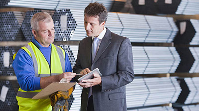 two business men putting bag in car boot